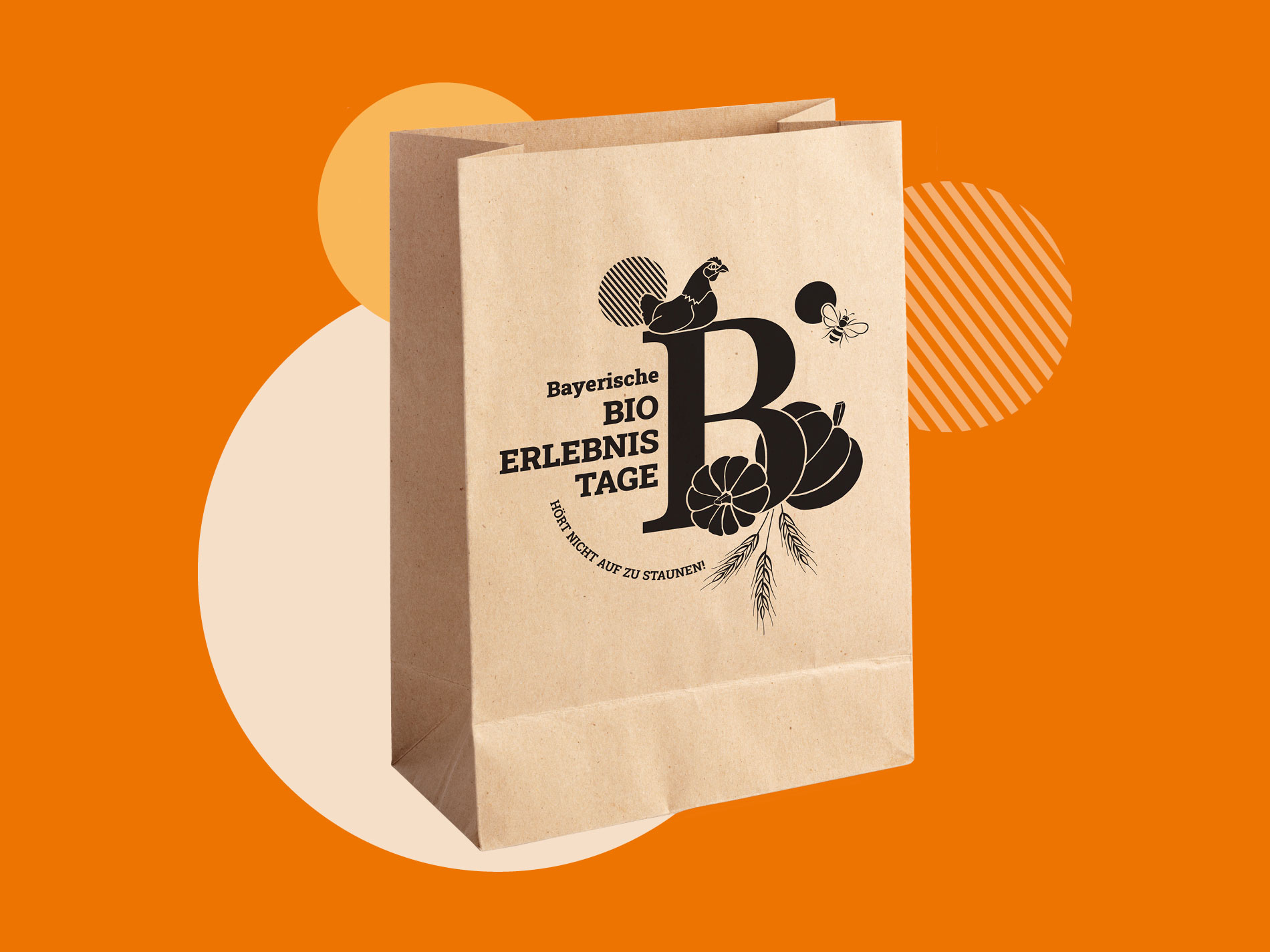 Das Bild zeigt eine braune Papiertüte mit einem schwarzen Logo und Design für die "Bayerischen Bio Erlebnistage", das den Slogan "Hört nicht auf zu staunen!" enthält.