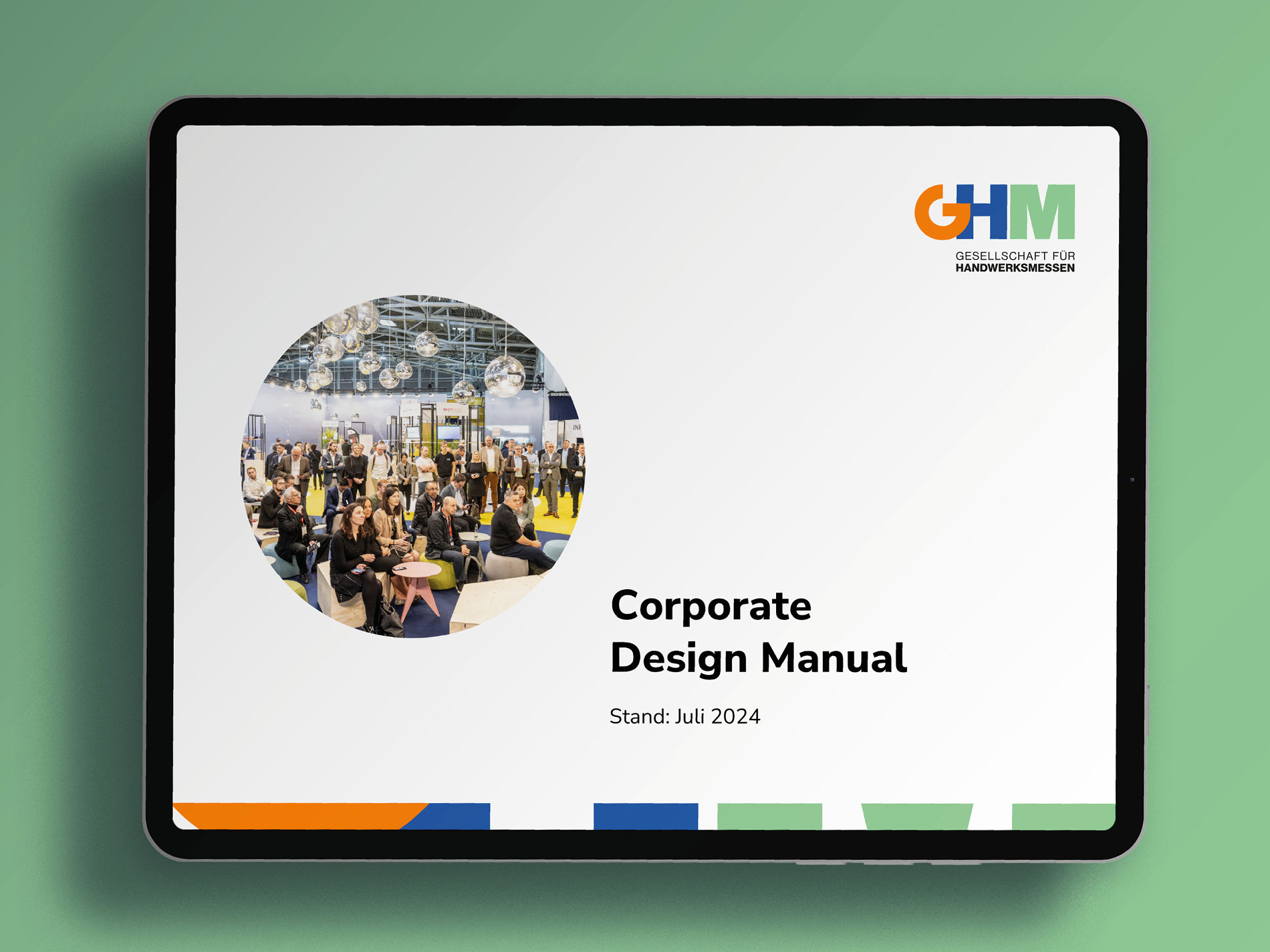 Das Bild zeigt ein Tablet, auf dem das "Corporate Design Manual" der Gesellschaft für Handwerksmessen (GHM) mit dem Stand Juli 2024 angezeigt wird, illustriert mit einem Foto von einer Messeveranstaltung.