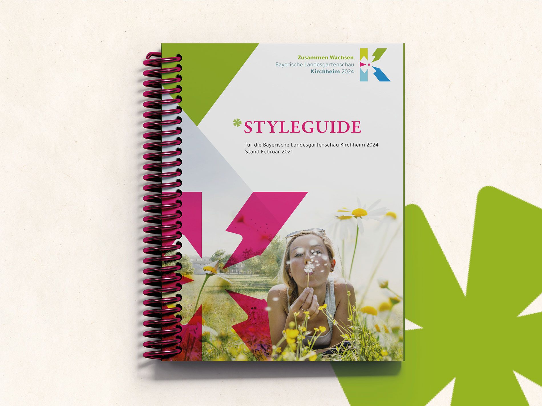 Das Bild zeigt einen Block mit dem Titel "Styleguide für die Bayerische Landesgartenschau Kirchheim 2024", der auf einer hellen Oberfläche liegt und ein Coverdesign mit floralen Motiven und lebendigen Farben hat.
