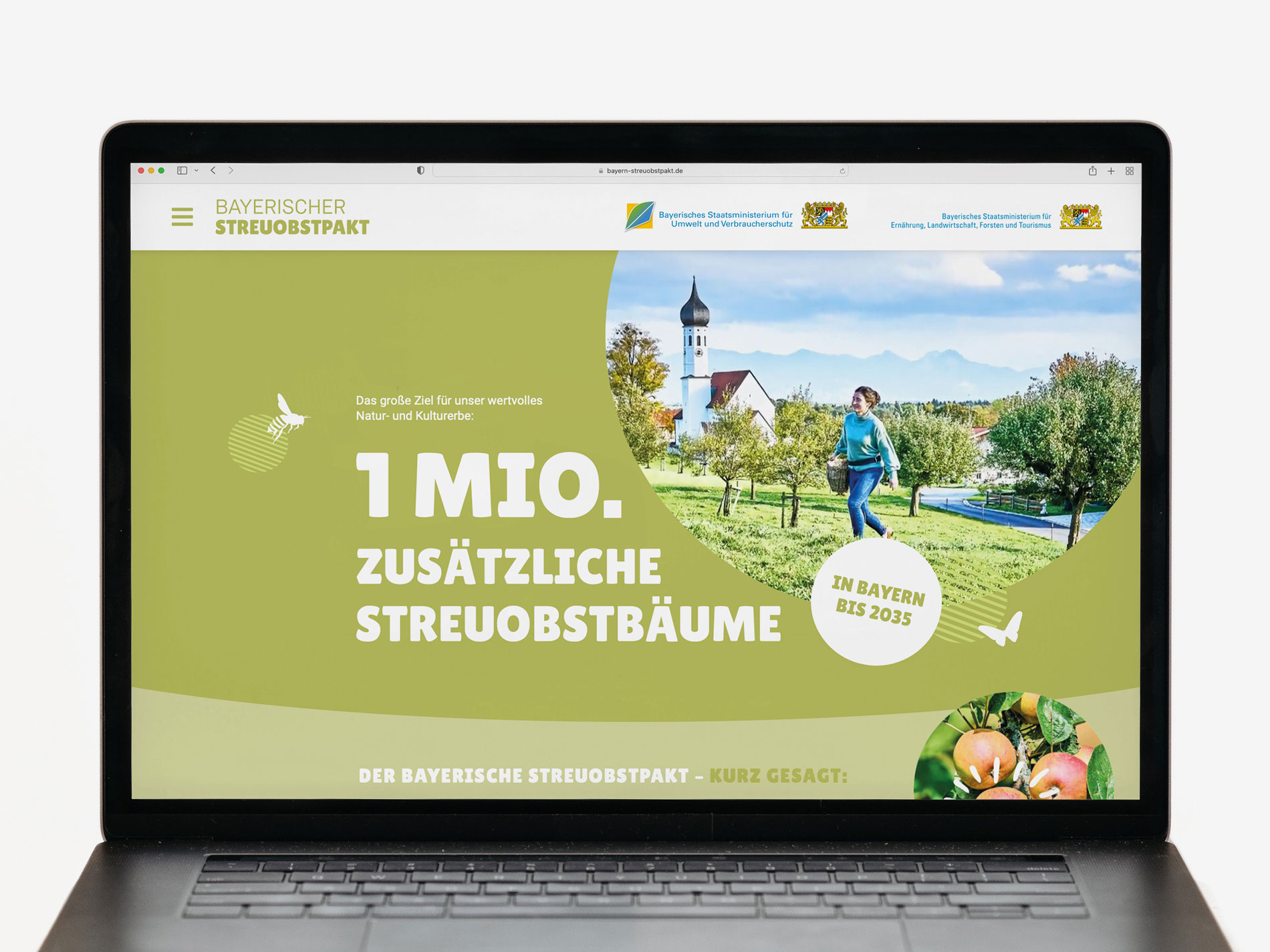 Das Bild zeigt den Bildschirm eines Laptops, auf dem eine Website des "Bayerischen Streuobstpakts" geöffnet ist. Der Text auf der Seite verkündet das Ziel, bis 2035 eine Million zusätzliche Streuobstbäume in Bayern zu pflanzen, um das wertvolle Natur- und Kulturerbe zu schützen. Im Hintergrund ist eine Frau zu sehen, die in einer Streuobstwiese läuft, und es sind Symbole von Äpfeln und Bienen dargestellt.