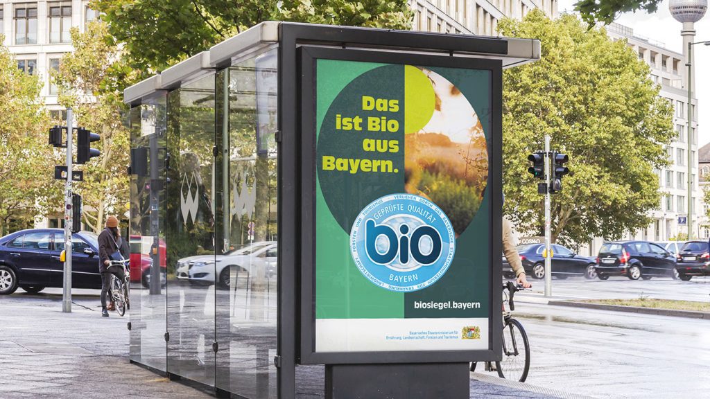 An einer Bushaltestelle ist ein Kampagnenmotiv vom bayerischen Bio-Siegel zu sehen.