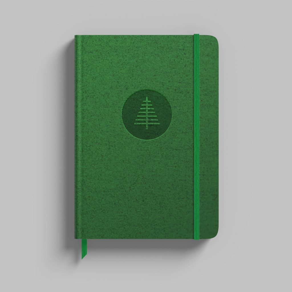 Dunkelgrünes Notizbuch mit geprägtem Tannen-Logo von Holzbau Fichtl auf dem Cover und grünem Verschlussband.