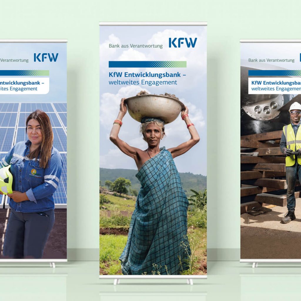 Drei Roll-up-Displays der KfW Entwicklungsbank mit dem Titel „weltweites Engagement" und Porträtmotiven aus verschiedenen Projektregionen.