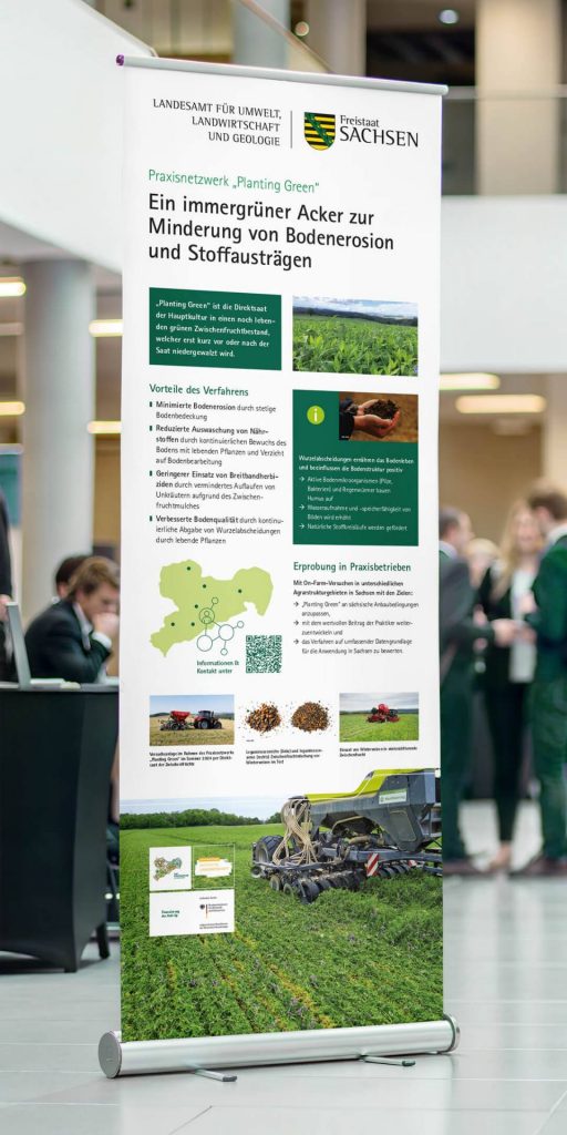 Roll-up-Display des LfULG Sachsen in einer Messehalle mit dem Titel „Ein immergrüner Acker zur Minderung von Bodenerosion und Stoffausträgen" zum Praxisnetzwerk „Planting Green".