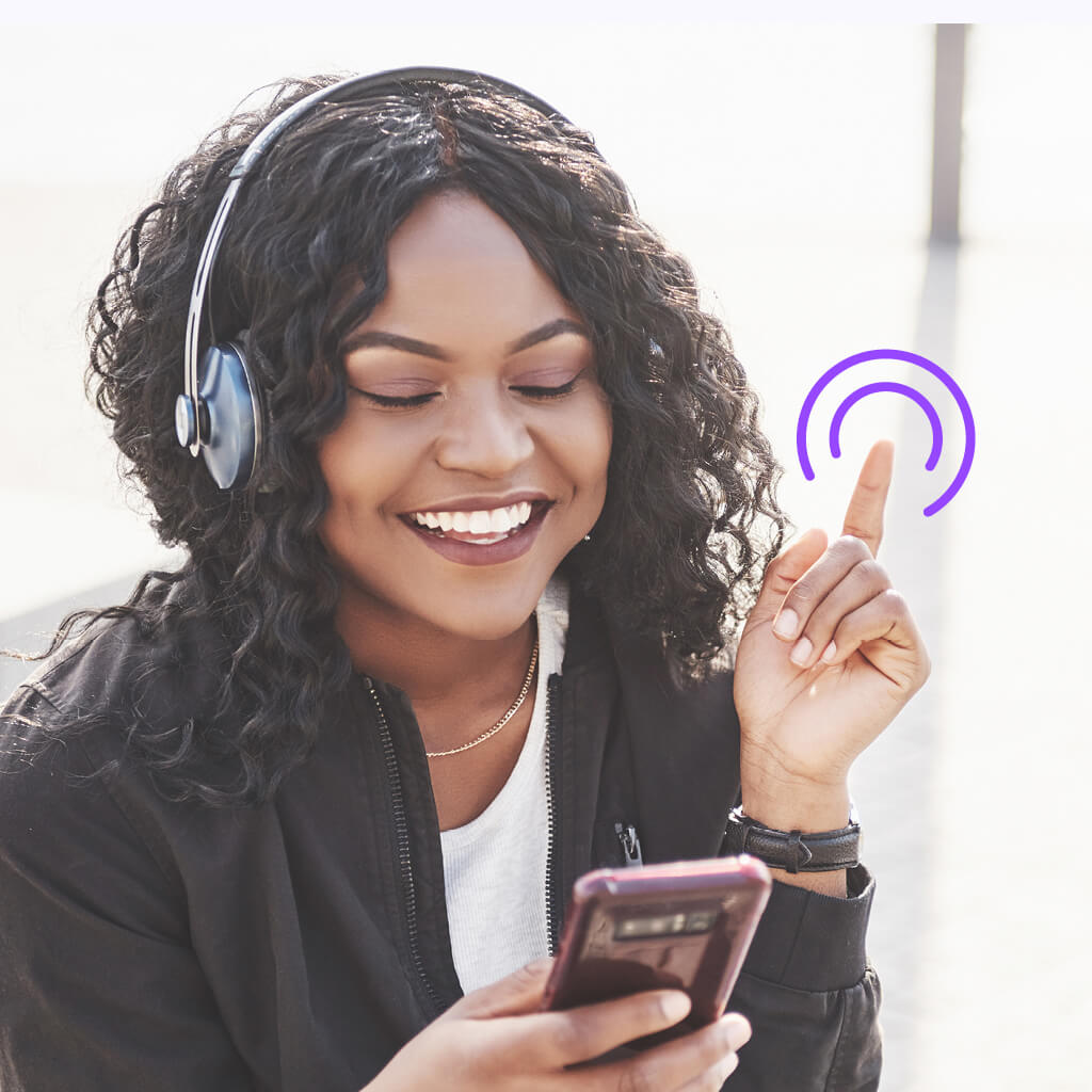 Porträt einer jungen Frau mit Kopfhörern, die lachend auf ihr Smartphone blickt – Bildmotiv aus der CareerOS-Kampagne.